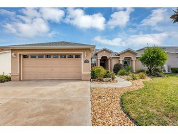 Charming single story home with tan exterior, attached garage, and beautiful landscaping at 15705 Sw 16Th Ter, Ocala, FL 34473