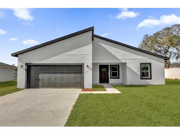 Modern home featuring a gray garage door, manicured lawn, and contemporary design at 420 Marion Oaks Crse, Ocala, FL 34473