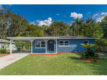 Charming single-story home with blue stone accents, a well-manicured lawn and a covered carport at 705 Liberty St, Eustis, FL 32726