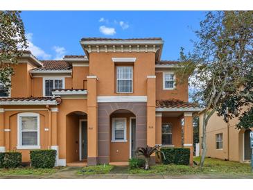 Charming two-story townhome featuring a stucco facade, red tile roof, and well-manicured landscaping at 7614 Acklins Rd, Kissimmee, FL 34747