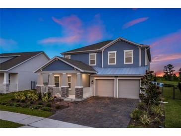 Charming two-story blue home with a two-car garage, a manicured front yard, and a covered porch at 9752 Petition Way, Orlando, FL 32832