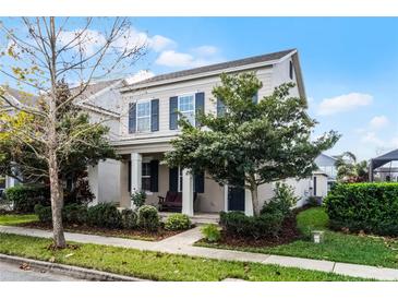 Charming two-story home features blue shutters, manicured landscaping, and inviting front porch with seating at 14214 Shocklach Dr, Winter Garden, FL 34787