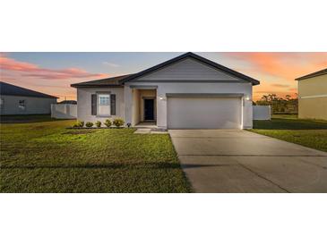 Charming single-Gathering home featuring a well-maintained lawn and a two-car garage under a warm, colorful sunset at 16390 Blooming Cherry Dr, Groveland, FL 34736