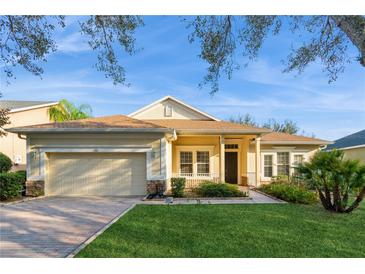 Charming single-story home with well-manicured lawn, a brick driveway, and neutral tan color at 182 Crepe Myrtle Dr, Groveland, FL 34736