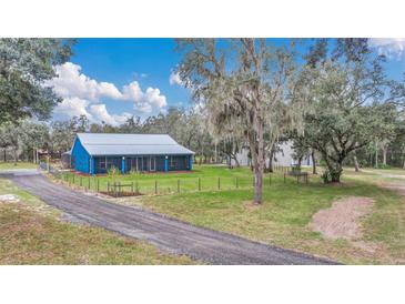 Charming blue home with a metal roof and inviting screened porch surrounded by lush greenery at 255 Butterfly Forest Rd, Geneva, FL 32732