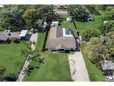 An aerial view showcasing a well-maintained lot with a screen-enclosed pool and long driveway at 290 Orange Ave, St Cloud, FL 34769
