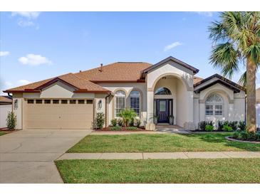 Inviting single-story home featuring manicured landscaping, arched windows, and a spacious two-car garage at 3012 Samosa Hill Cir, Clermont, FL 34714