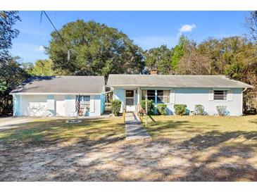 Charming single-story home featuring an American flag, lush greenery and light blue paint at 530 Mckenzie Rd, Lake Helen, FL 32744
