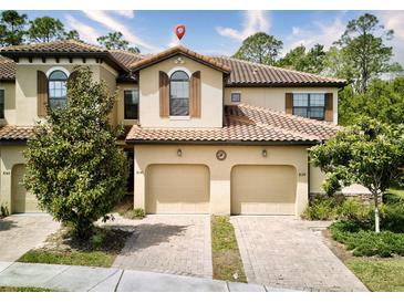 Charming townhome with a terra cotta tile roof and two-car garage, with a brick paver driveway at 8141 Roseville Blvd, Davenport, FL 33896