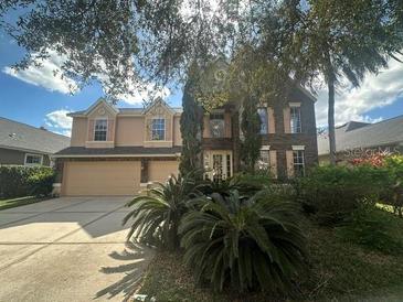 Traditional-style home with a manicured front yard and an attached two-car garage at 10446 Stone Glen Dr, Orlando, FL 32825