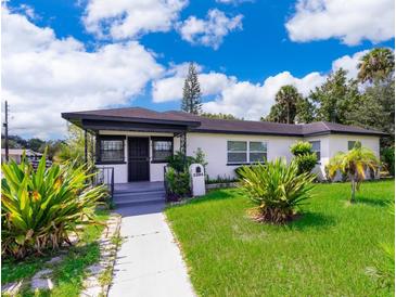 Charming one-story home featuring a well-manicured lawn and lush, tropical landscaping at 2394 Orange Center Blvd, Orlando, FL 32805