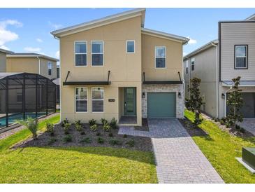 Modern two-story home featuring desert-tone walls, manicured lawn, stone accents, and attached garage at 2908 Protagonist St, Kissimmee, FL 34746