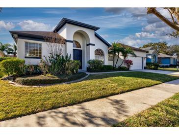 Charming home featuring a manicured lawn, lush landscaping, and an arched entryway that adds curb appeal at 418 Laurenburg Ln, Ocoee, FL 34761