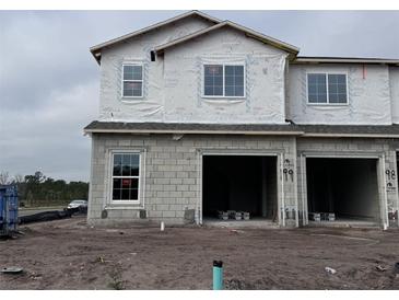 Exterior of a home under construction with visible framing, windows, and garage doors at 5116 Rain Shadow Dr, St Cloud, FL 34772