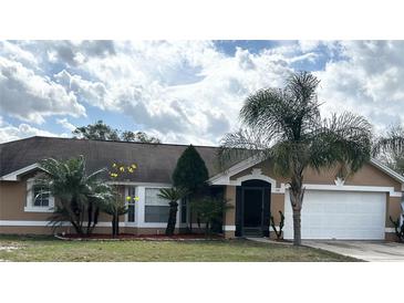 Charming single-story home featuring a well-manicured lawn and lush tropical landscaping at 121 Loma Bonita Dr, Davenport, FL 33837