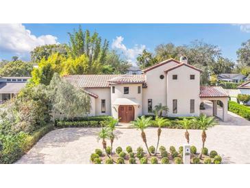 Stunning Mediterranean-style home with a red tile roof, mature landscaping, and a circular driveway at 135 James Pl, Maitland, FL 32751