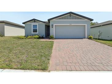 Charming single-Gathering home features a brick driveway, a 2-car garage, and well-maintained lawn at 1522 Mermaid Way, Haines City, FL 33844