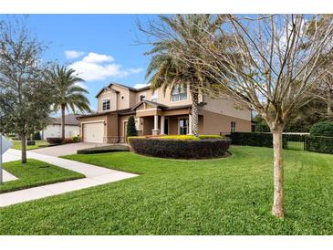Landscaped front yard with lush green grass, palm trees, and colorful shrubbery at 1938 Filly Trl, Oviedo, FL 32765