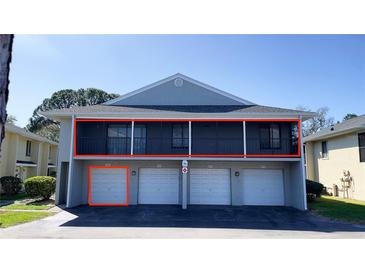 A two-story condo building featuring garages and a second-story screened in balcony at 4448 Pinebark Ave # 56-1, Orlando, FL 32811