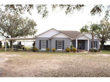 Charming single-story home with a grey exterior, a boat port, and lush landscaping at 9130 Laws Rd, Clermont, FL 34714