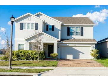 Charming two-story home with landscaped yard, brick driveway, and an attached garage at 9228 Halsey Dr, Groveland, FL 34736