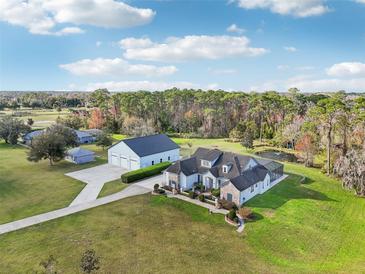 Expansive aerial view of estate featuring large home, guesthouse, pond, and lush green lawn at 1220 Lake Mills Rd, Chuluota, FL 32766