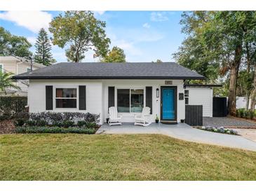 Charming single-story home featuring a blue front door, two white rocking chairs, and a well-maintained lawn at 1410 Osceola Ct, Orlando, FL 32806