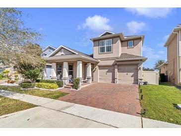 Two-story home featuring a two-car garage and a charming front porch with well-manicured landscaping at 15772 Murcott Harvest Loop, Winter Garden, FL 34787