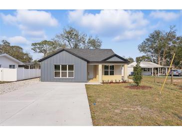 Charming single-story home features a modern gray exterior, new concrete driveway and manicured lawn at 355 Anderson Dr, Groveland, FL 34736