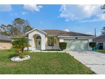 Charming single-story home featuring a two-car garage, arched entryway, and well-manicured front yard at 5173 Clarion Oaks Dr, Orlando, FL 32808