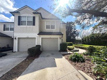 Two-story townhome with attached garages, manicured landscaping, and walkway to a nearby lake at 6292 Twain Street # 108, Orlando, FL 32835