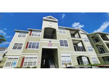 View of the condo building showing the facade, unit number, stairwell, and balconies against a blue sky at 8103 Lillies Way # 202, Orlando, FL 32825