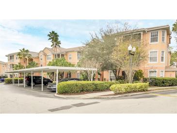 Exterior view of a peach-colored building with covered parking and manicured landscaping at 13500 Turtle Marsh Loop # 839, Orlando, FL 32837