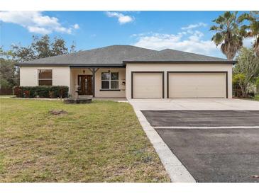 Charming single-story home with a two-car garage, well-manicured lawn, and beautiful mature trees at 18468 Sabal St, Orlando, FL 32833