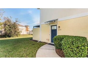 Inviting front entrance with a blue door, manicured bushes, and a well-maintained lawn at 2023 Grand Oak Dr, Kissimmee, FL 34744