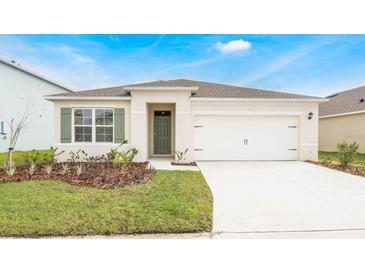 Charming single-story home with neutral paint, green shutters, landscaped yard, and attached two car garage at 2980 Moulin Rd, Davenport, FL 33837