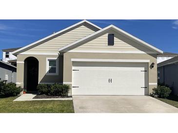 A charming single-story home featuring a two-car garage, manicured lawn, and neutral-toned siding at 2981 Moulin Rd, Davenport, FL 33837