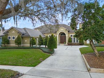 Well-manicured front exterior featuring a circular driveway, lush lawn, and mature trees at 3569 Bellington Dr, Orlando, FL 32835