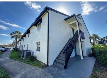 Two-story condo building featuring neutral-toned stucco, black trim, a staircase and well-maintained landscaping at 4405 S Semoran Blvd # 7, Orlando, FL 32822