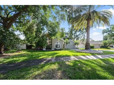 Beautifully landscaped front yard with a large palm tree and mature trees around the house at 703 E Lakeshore Dr, Ocoee, FL 34761