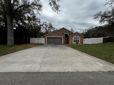 Charming single-story home featuring a spacious driveway and a well-maintained lawn with decorative white fencing at 7132 Laurel Hill Dr, Orlando, FL 32818