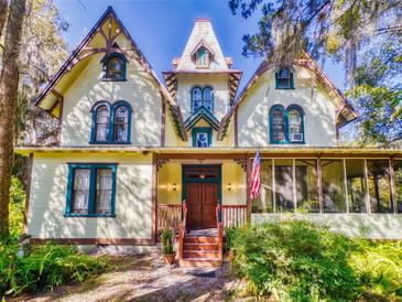 Charming yellow two-story home with Queen Anne architecture, a quaint porch, and an American flag at 3471 Whitner Way, Sanford, FL 32773