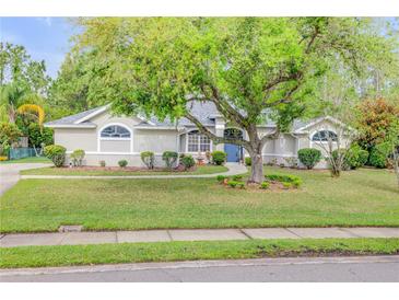 Inviting single-story home with lush green lawn, mature shade tree, and manicured landscaping at 27 Foxhunter Flt, Ormond Beach, FL 32174