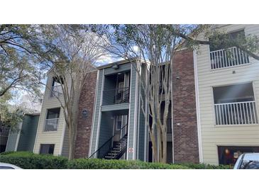 A multi-story condo building with brick and blue-painted siding, shadowed by bare trees, and green bushes at 5016 Park Central Dr # 2231, Orlando, FL 32839