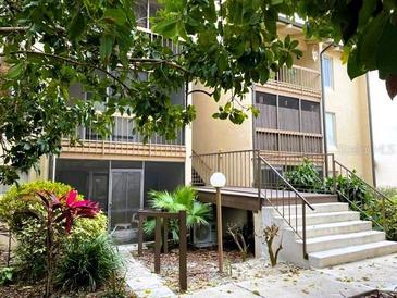 Condo building with mature trees, landscaping, and exterior stairs leading to the units at 586 Orange Dr # 114, Altamonte Springs, FL 32701