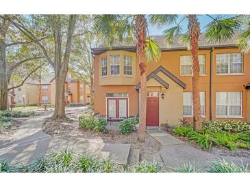 Charming townhome with a red door, lush landscaping, and a cozy patio area in a desirable community at 6356 Raleigh St # 1512, Orlando, FL 32835