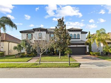 Elegant two-story home with a manicured lawn, paver driveway, tile roof, and a beautiful architectural design at 8515 Morehouse Dr, Orlando, FL 32836