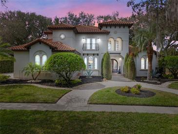 Elegant Mediterranean-style home featuring a red tile roof and beautifully landscaped front yard at dusk at 8826 Southern Breeze Dr, Orlando, FL 32836