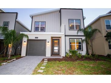 Attractive two-story home featuring a modern color palette and well-manicured landscaping at 8988 Cabot Cliffs Dr, Champions Gate, FL 33896