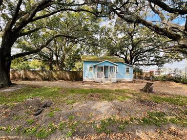 Charming blue house with a quaint front porch, surrounded by mature trees and a partially fenced yard at 9350 2Nd Ave, Orlando, FL 32824